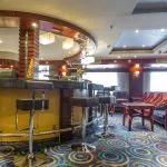 A stylish lounge bar on the Blue Shadow i Nile Cruise, with comfortable seating, a well-stocked bar, and a large window overlooking the river.