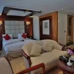 The luxurious suite on the Blue Shadow i Nile Cruise, featuring a comfortable king-size bed, a separate seating area, and a large window with a scenic view.