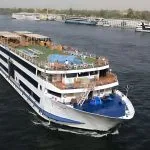 MS Blue Shadow iii Nile Cruise ship cruising on the Nile River, showcasing its multi-deck design, sun deck, and rooftop swimming pool.