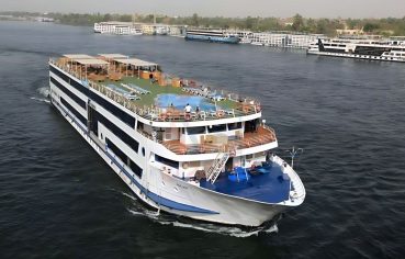 MS Blue Shadow iii Nile Cruise ship cruising on the Nile River, showcasing its multi-deck design, sun deck, and rooftop swimming pool.