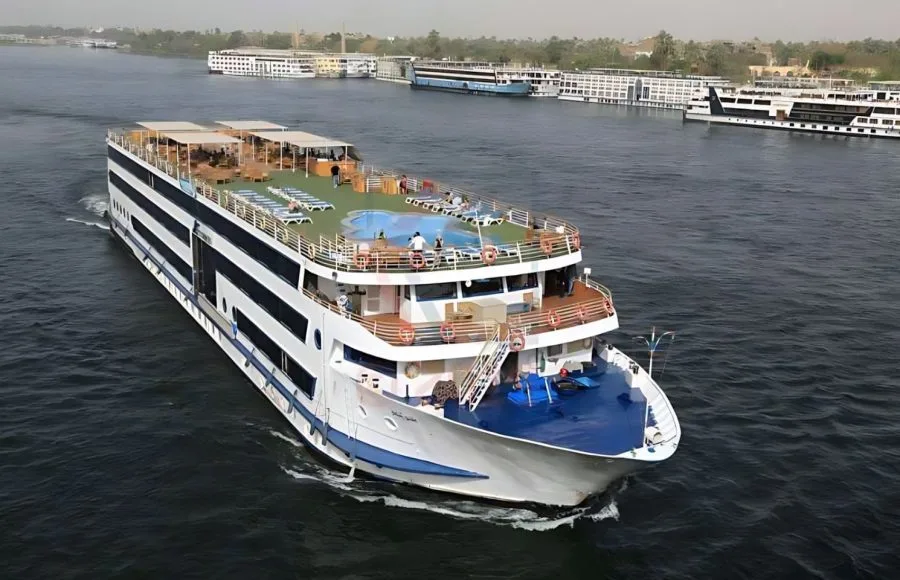 MS Blue Shadow iii Nile Cruise ship cruising on the Nile River, showcasing its multi-deck design, sun deck, and rooftop swimming pool.