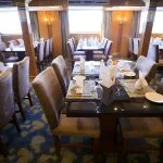 Dining area of the Blue Shadow iii Nile Cruise, with tables set for guests and large windows offering views of the river.