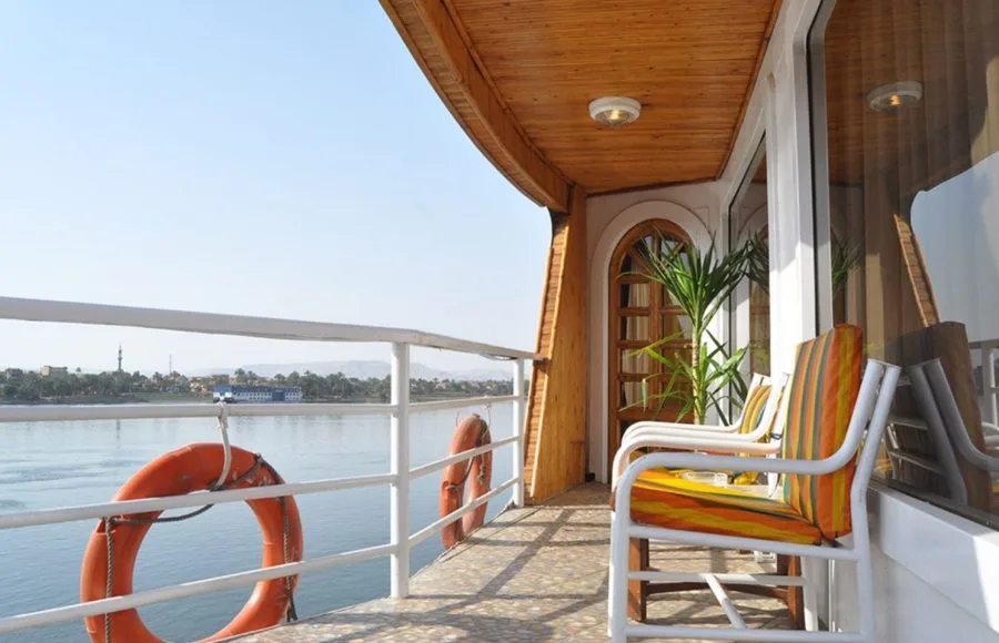 A captivating view of the Nile River from the private balcony of a cabin aboard the luxurious HS Solaris I Nile Cruise, featuring comfortable chairs and a lifebuoy.