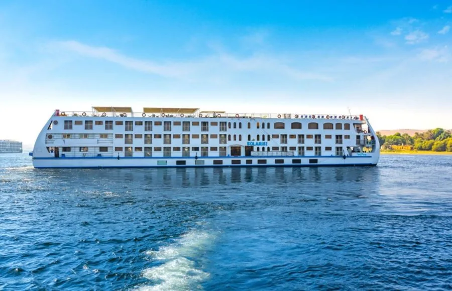 The impressive HS Solaris I Nile Cruise ship moving gracefully on the sparkling waters of the Nile River under a clear blue sky.