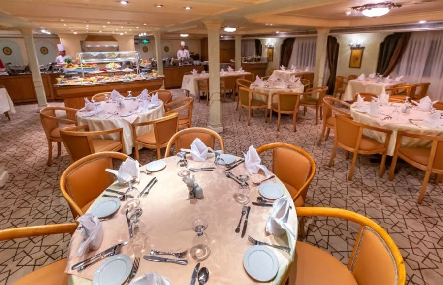 A well-appointed restaurant on the HS Solaris I Nile Cruise with neatly set tables and a buffet station, ready to serve a variety of delicious meals.