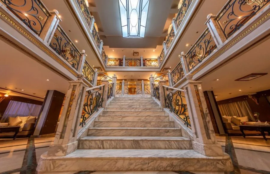 The grand, multi-level marble staircase in the stunning lobby of the Solaris II Nile Cruise, featuring ornate gold railings and elegant design