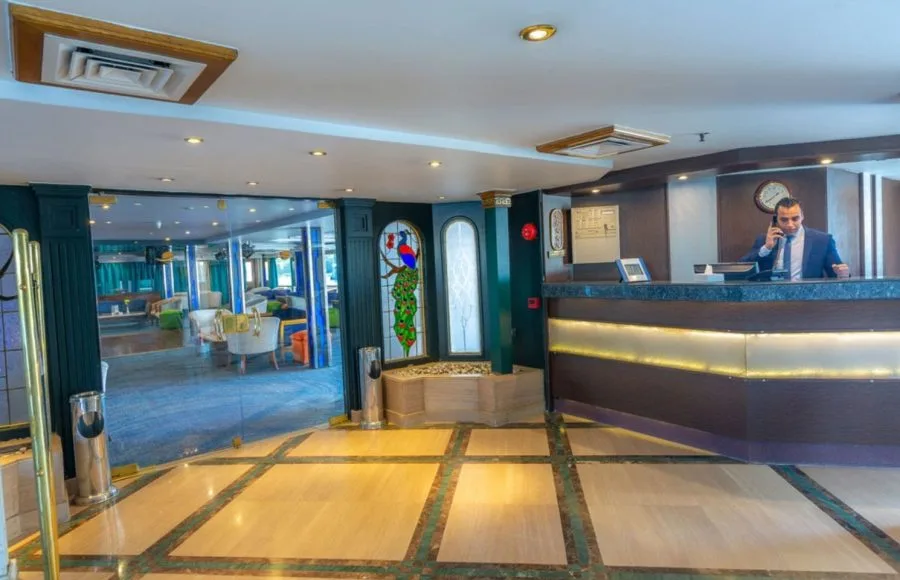 The elegant reception and lobby area of the Solaris II Nile Cruise, featuring a modern front desk with a staff member and a view into the stylish lounge