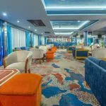 The stylish lounge and bar area aboard the Solaris II Nile Cruise, featuring vibrant blue and orange seating and a modern aesthetic