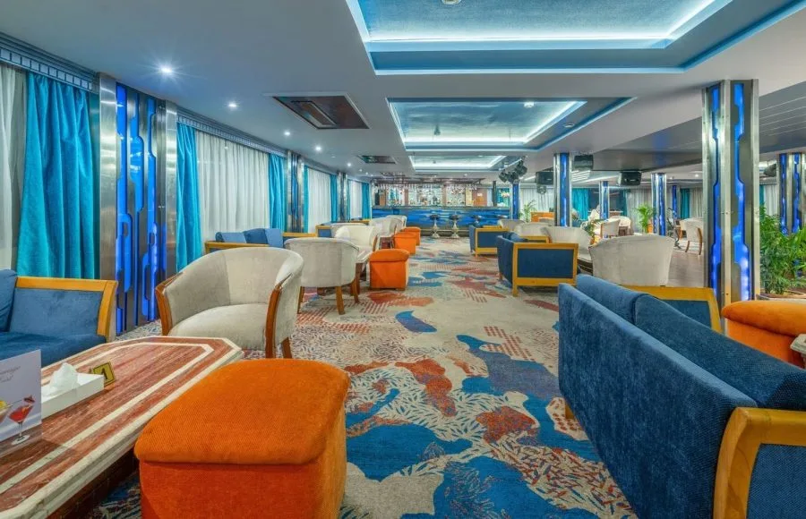 The stylish lounge and bar area aboard the Solaris II Nile Cruise, featuring vibrant blue and orange seating and a modern aesthetic