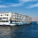 The majestic Solaris II Nile Cruise ship gracefully sailing on the Nile River alongside a traditional felucca under a clear blue sky