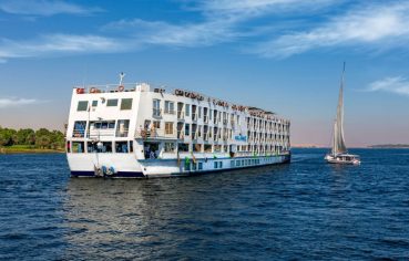 The majestic Solaris II Nile Cruise ship gracefully sailing on the Nile River alongside a traditional felucca under a clear blue sky