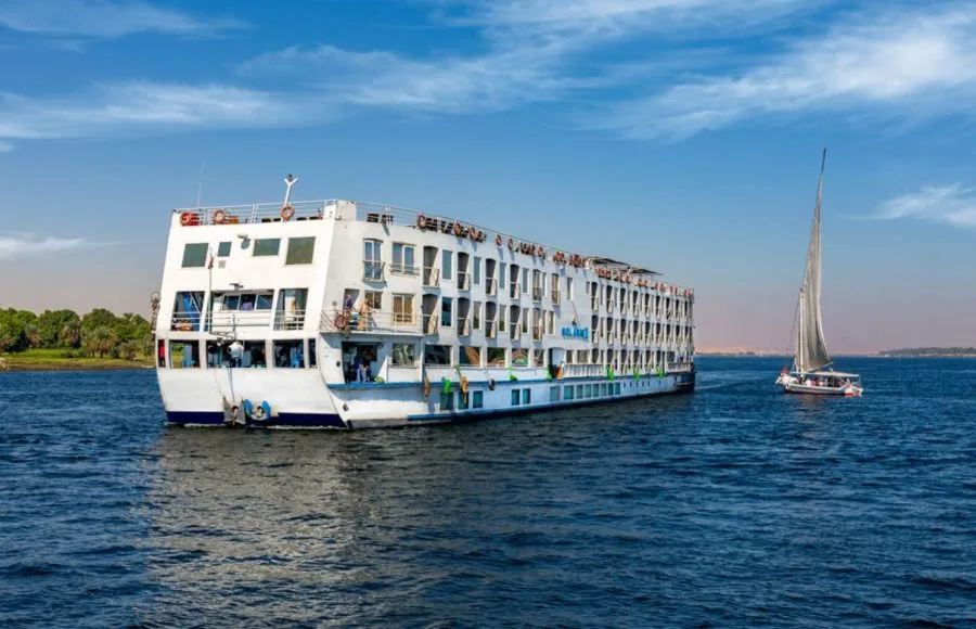 The majestic Solaris II Nile Cruise ship gracefully sailing on the Nile River alongside a traditional felucca under a clear blue sky