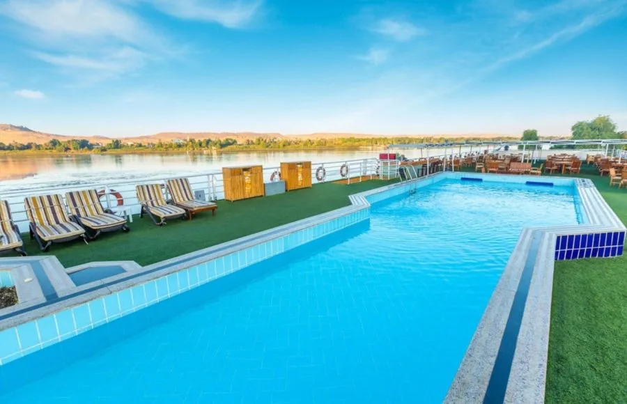The beautiful sundeck on the Solaris II Nile Cruise, featuring a sparkling blue swimming pool and multiple sun loungers overlooking the Nile River