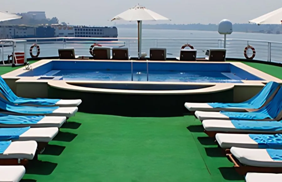 The vibrant sun deck of the Al Kahila Nile cruise features a refreshing swimming pool and rows of inviting loungers with blue towels.