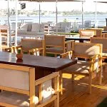 The scenic outdoor dining area on the upper deck of the Al Kahila Nile cruise, with tables and chairs overlooking the river.