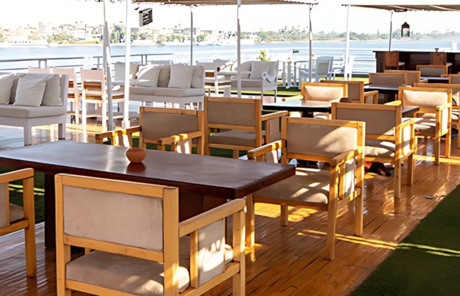 The scenic outdoor dining area on the upper deck of the Al Kahila Nile cruise, with tables and chairs overlooking the river.