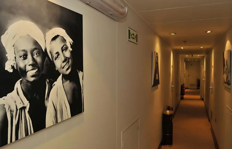 An elegant corridor on the MS Alexander The Great Nile Cruise ship, featuring a large black and white framed photo and wood accents.