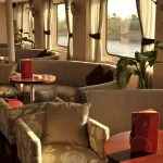 Interior view of the "Red Fiesta" restaurant on the MS Alexander The Great Nile cruise ship, with panoramic windows overlooking the Nile.