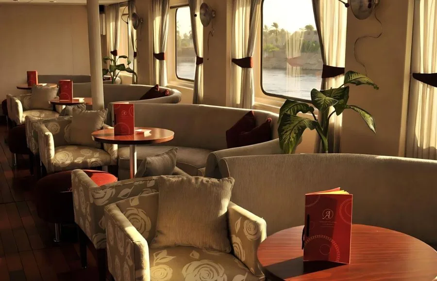 Interior view of the "Red Fiesta" restaurant on the MS Alexander The Great Nile cruise ship, with panoramic windows overlooking the Nile.