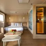 An interior photo of a suite on the MS Alexander The Great Nile cruise ship, showing the bed, couch, and window view.