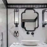 The luxurious bathroom in the suite aboard the Movenpick MS Darakum Nile Cruise features elegant marble tiling a modern rain shower and a stylish black-framed mirror