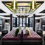 The vibrant and luxurious main lounge of the Movenpick MS Darakum Nile Cruise features rich purple seating dark wood accents and an ornate stained-glass ceiling