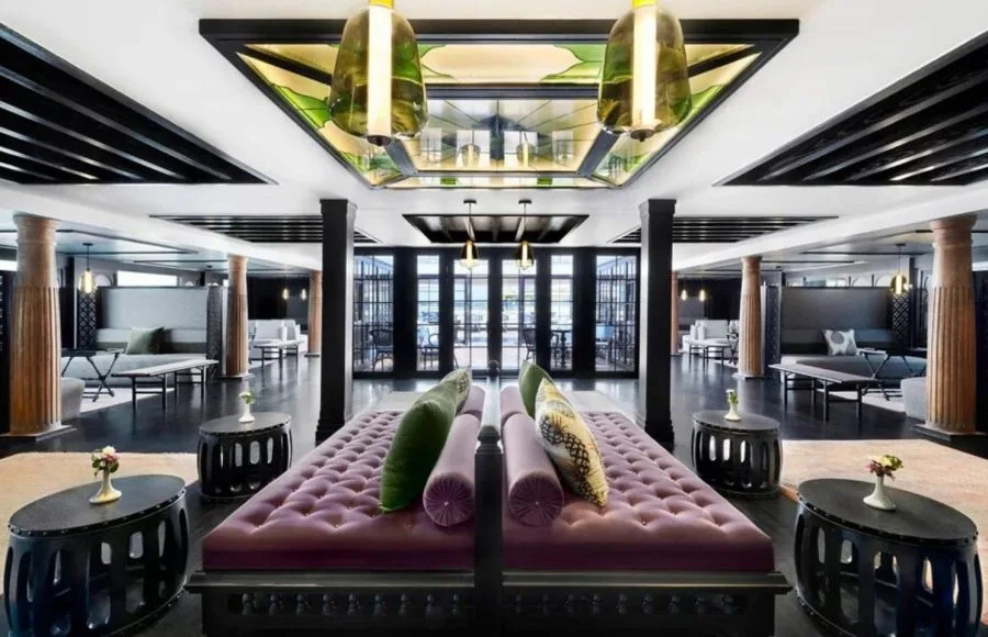The vibrant and luxurious main lounge of the Movenpick MS Darakum Nile Cruise features rich purple seating dark wood accents and an ornate stained-glass ceiling
