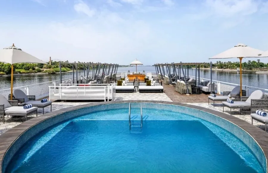 The spacious sun deck of the Movenpick MS Darakum Nile Cruise features a refreshing circular swimming pool surrounded by comfortable loungers and umbrellas perfect for relaxing along the river