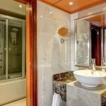 Luxury marble bathroom with vessel sink and multi-jet shower cabin on cruise ship.