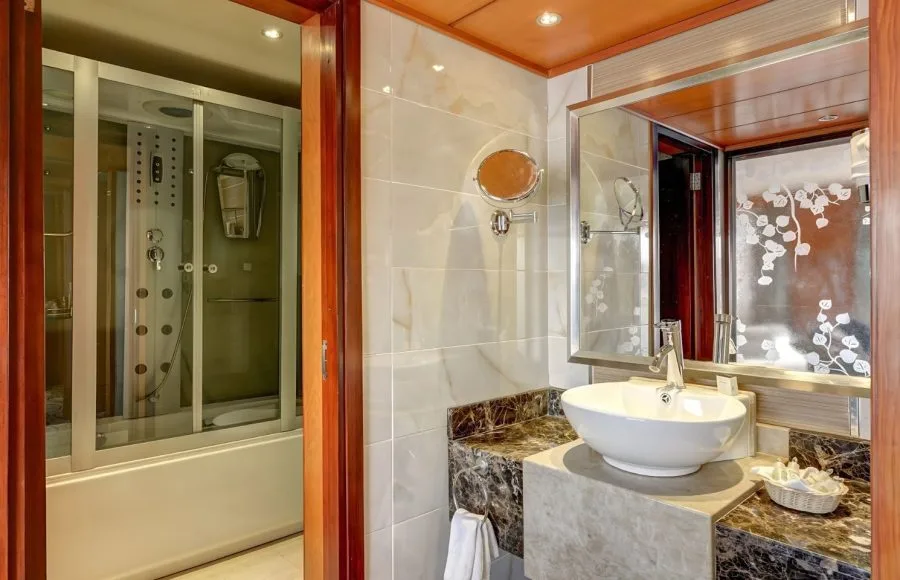 Luxury marble bathroom with vessel sink and multi-jet shower cabin on cruise ship.
