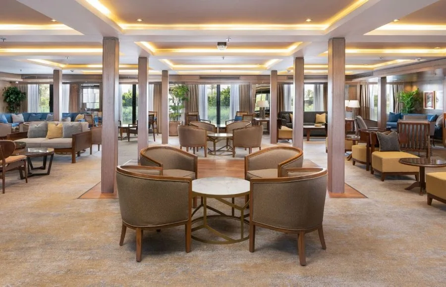 The spacious and well-lit lounge area on the MS Jaz Regent Nile Cruise, featuring comfortable armchairs and sofas arranged in inviting seating groups.