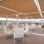 The sun deck of the MS Jaz Regent Nile Cruise, featuring a small pool, numerous lounge chairs with umbrellas, and a view of the Nile River banks.