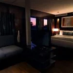 An elegant suite on MS Le Fayan with a bed, sofa, television, and a window offering a scenic view.