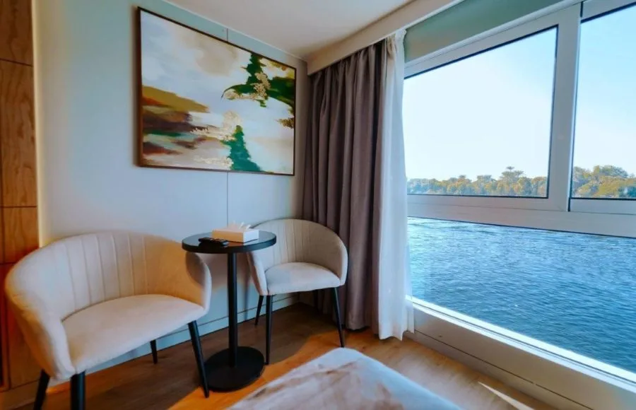 Enjoy the stunning Nile river view from a comfortable MS Miriam Nile Cruise cabin with stylish seating and modern decor