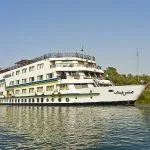 The exterior view of the large white and blue MS Miriam nile cruise ship sailing on the Nile river