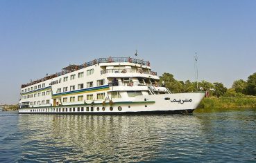 The exterior view of the large white and blue MS Miriam nile cruise ship sailing on the Nile river