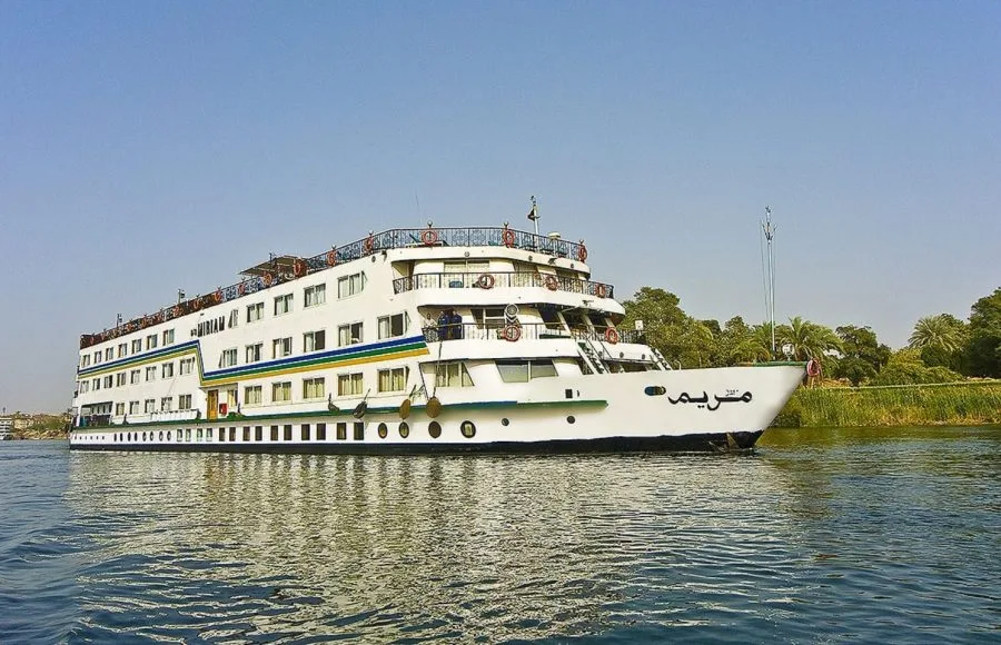 The exterior view of the large white and blue MS Miriam nile cruise ship sailing on the Nile river