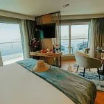 A luxurious standard cabin on the MS Miriam Nile Cruise featuring a comfortable bed, sitting area, and private balcony overlooking the water