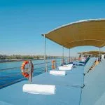 Guests relaxing on comfortable sun loungers under a shaded canopy on the sun deck of the MS Miriam Nile Cruise