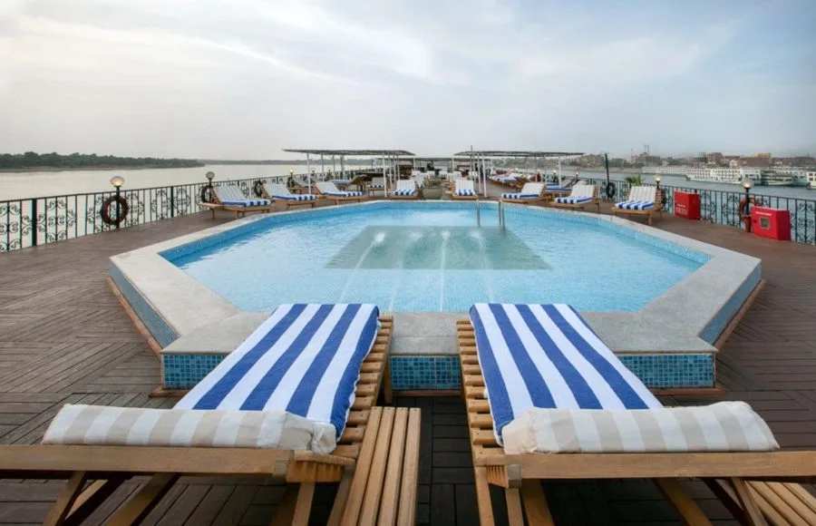 The sun deck pool and striped loungers with a river backdrop on the luxurious MS Miriam nile cruise ship