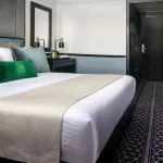 Comfortable and modern suite with crisp white bedding and teal accents, providing a peaceful retreat on the Movenpick Hamees Nile Cruise.