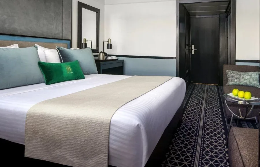 Comfortable and modern suite with crisp white bedding and teal accents, providing a peaceful retreat on the Movenpick Hamees Nile Cruise.