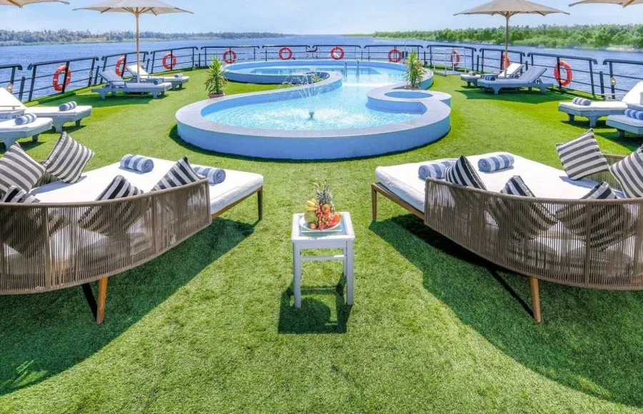 The beautiful outdoor pool and sun loungers on the upper deck of the luxury Movenpick Hamees Nile Cruise offering refreshing views of the river.