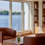 The cozy library aboard the Ms Royal Lotus Nile Cruise offers comfortable seating and panoramic windows overlooking the river