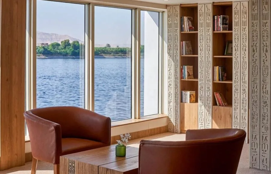 The cozy library aboard the Ms Royal Lotus Nile Cruise offers comfortable seating and panoramic windows overlooking the river
