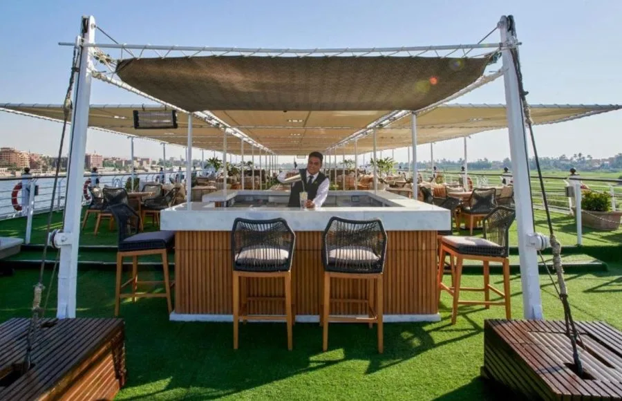 A bartender prepares a drink at the stylish sun deck bar on the ms movenpick royal lotus nile cruise overlooking the river.