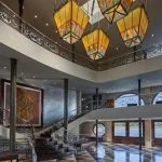 The grand, two-story lobby of the Movenpick MS Sunray with a curved staircase and distinctive Moroccan-style lamps.