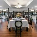 The elegant main restaurant on the Movenpick MS Sunray set with tables and a central buffet for dining on the Nile Cruise.