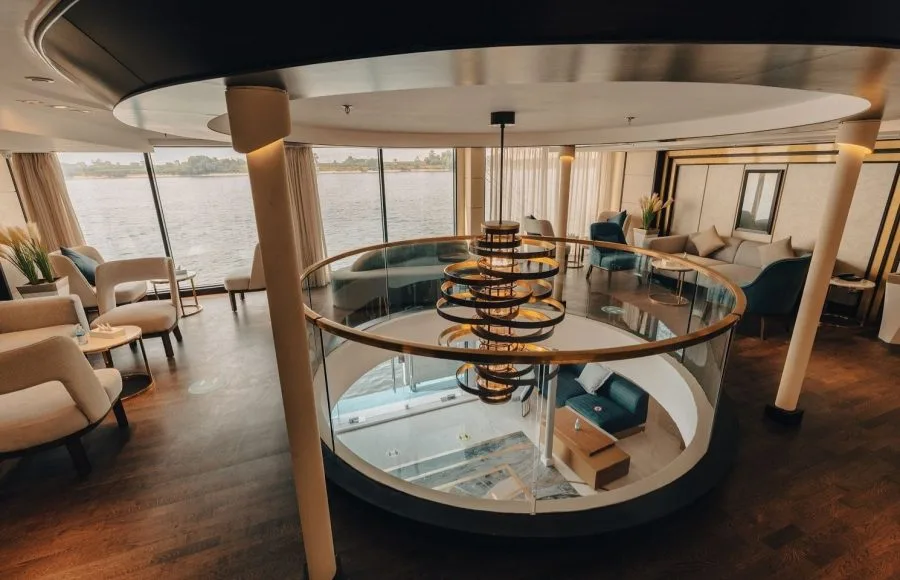 Two-story circular ship lounge with floor-to-ceiling windows and modern chandelier.