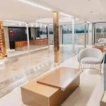 Modern cruise ship lobby with reception desk, seating, and gold accents.